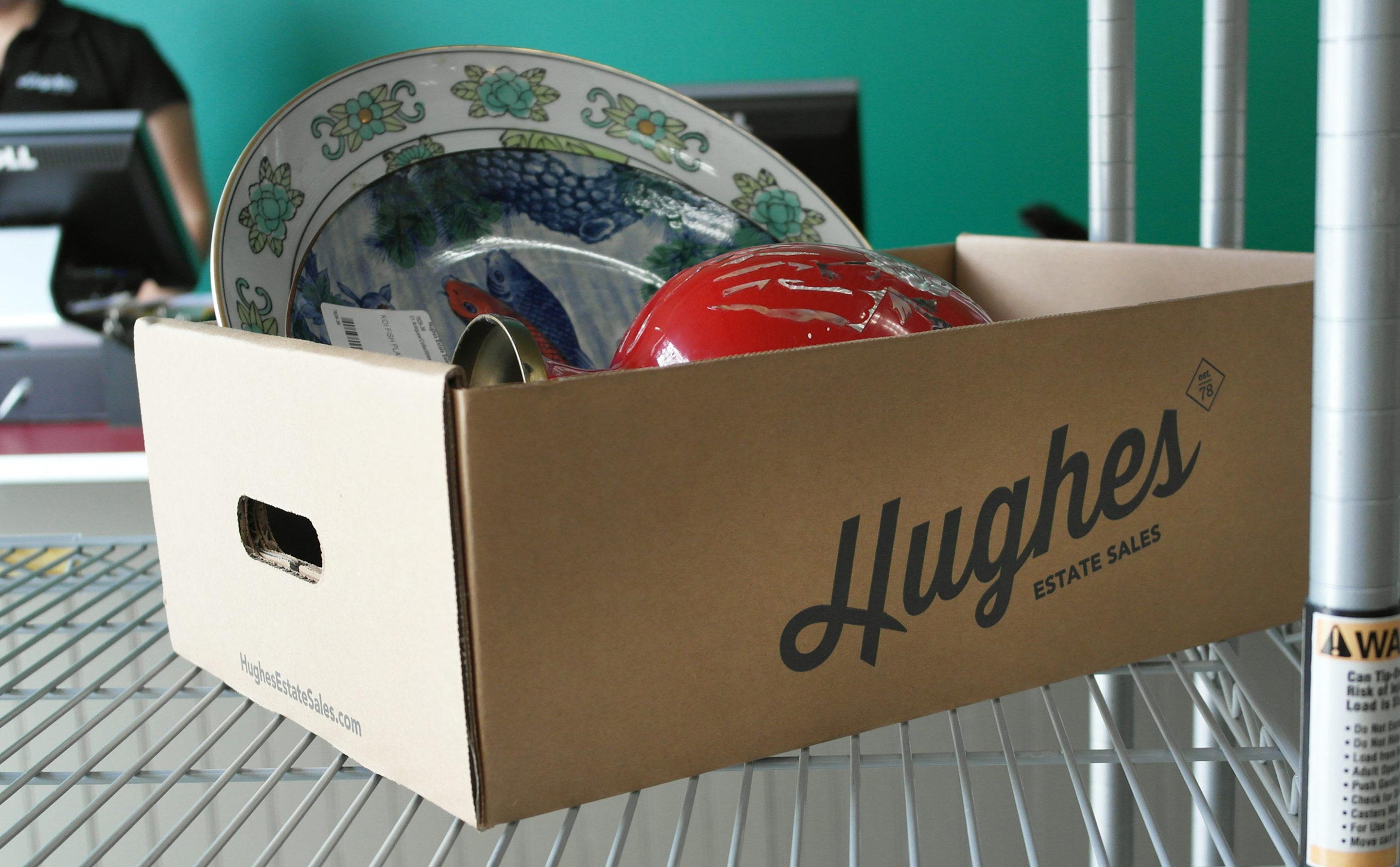 branded hughes estate sales box with dishes in it