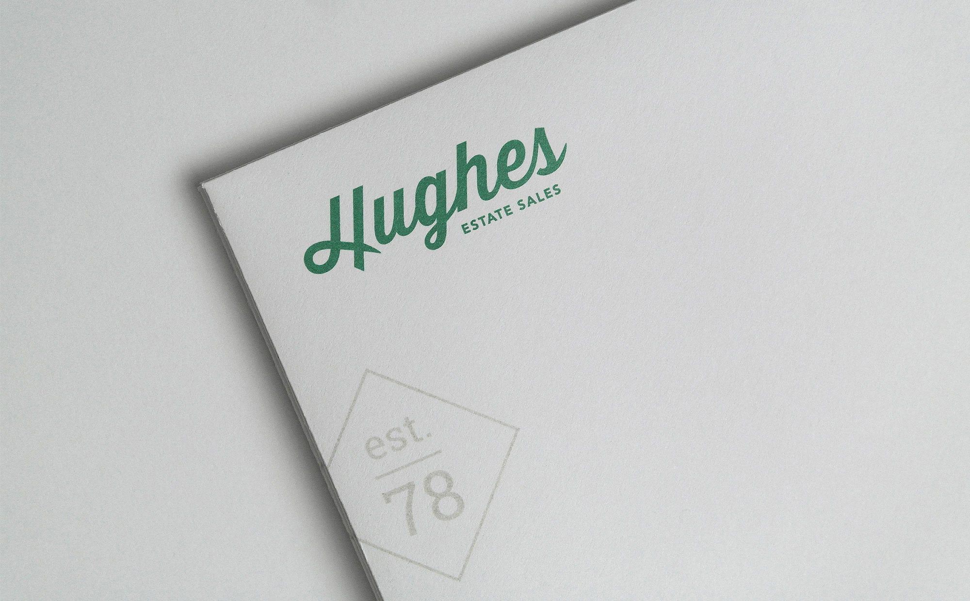 close up of hughes logo in green on antique gray paper with "est 78" watermark