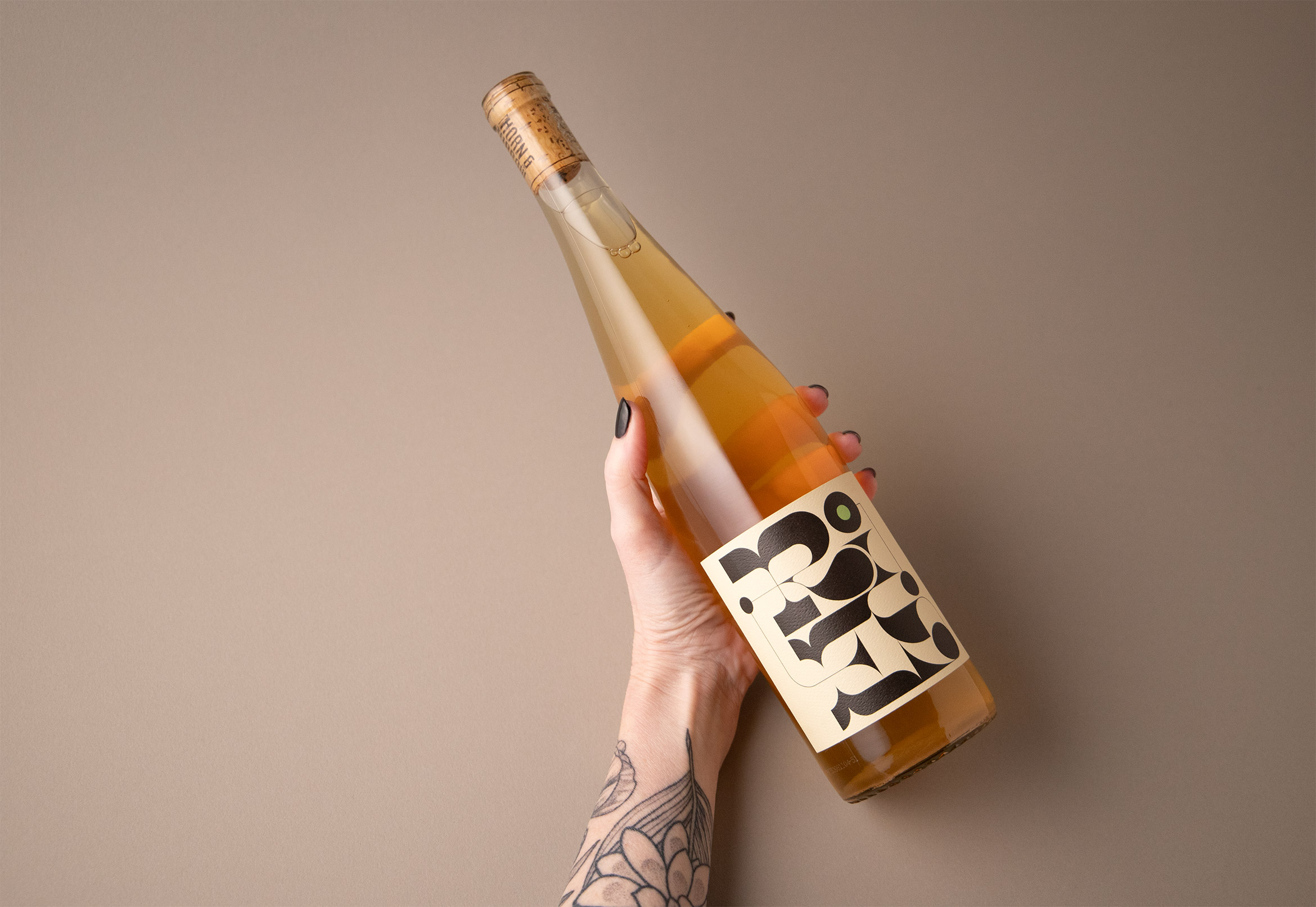 hand holding white wine label, arm has tattoos