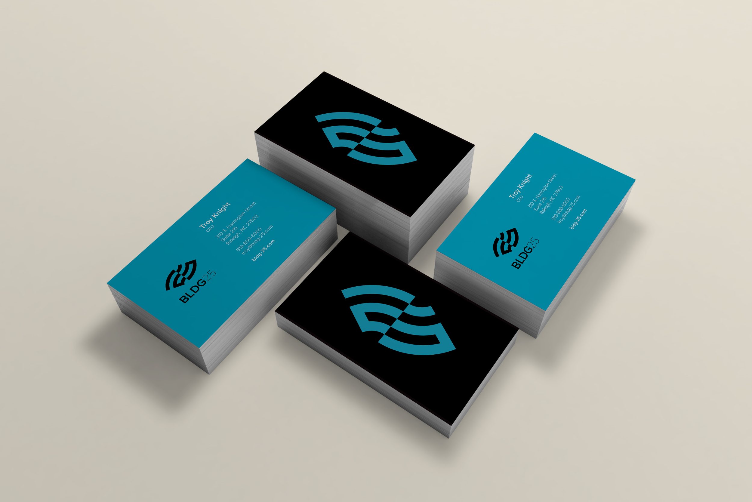 stack of business cards with bldg25 logo on front in aqua on black with an aqua back