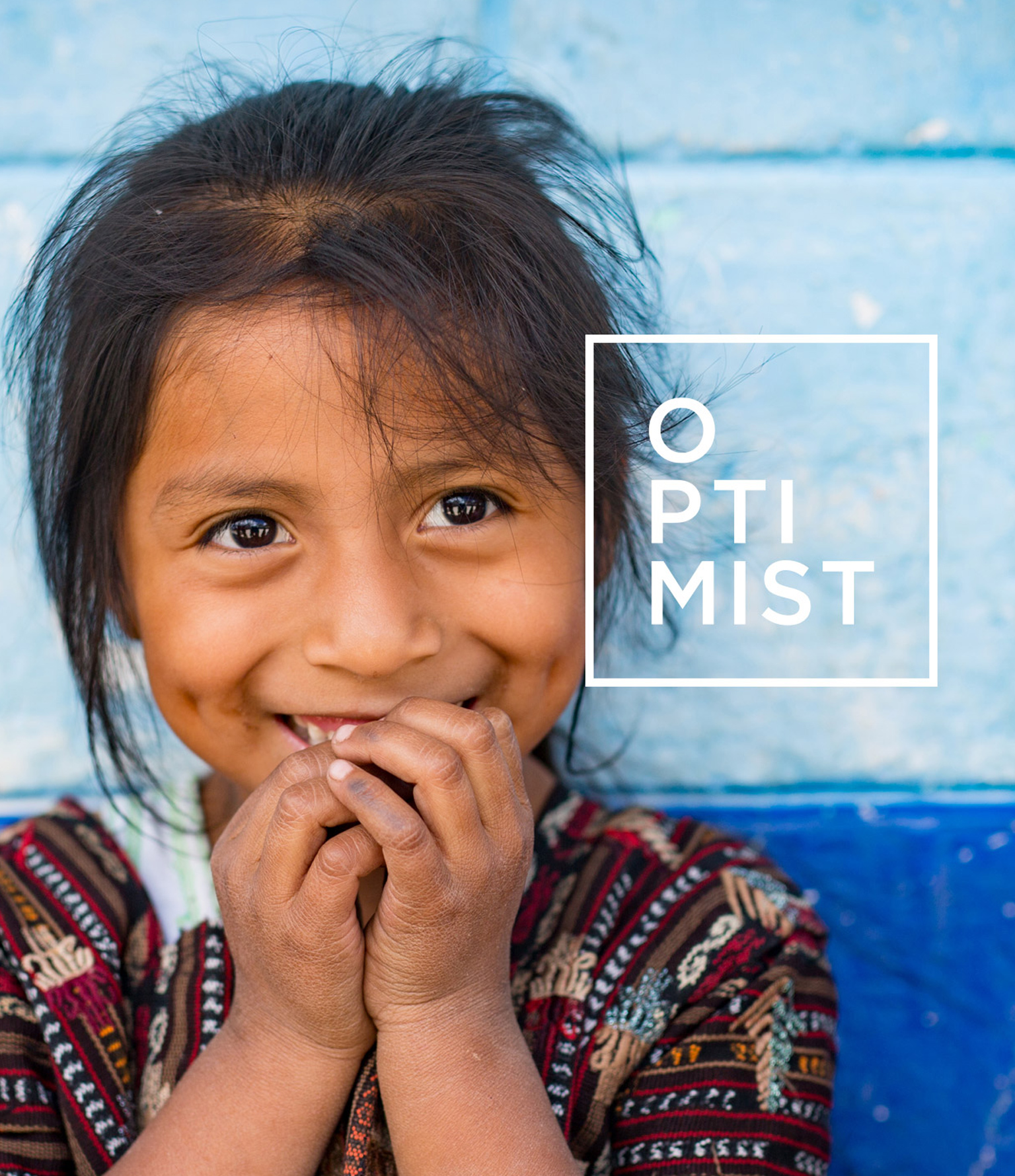 honduran girl smiling with hands in mouth in front of blue wall with optimist logo on image