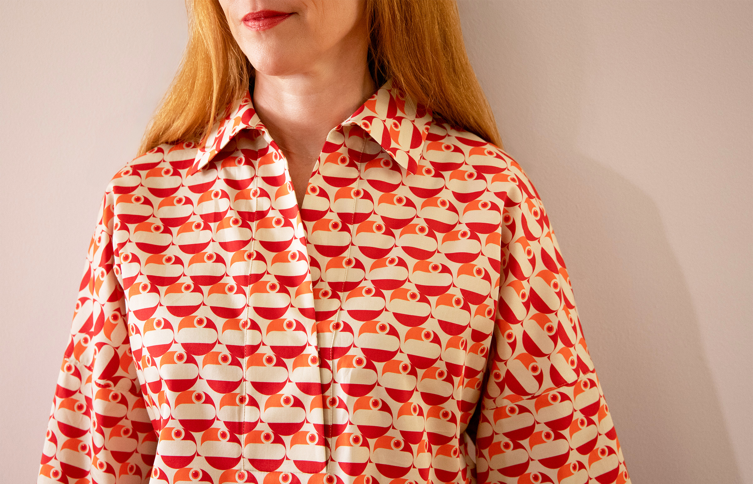 red haired woman wearing a shirt with red and orange pelican pattern