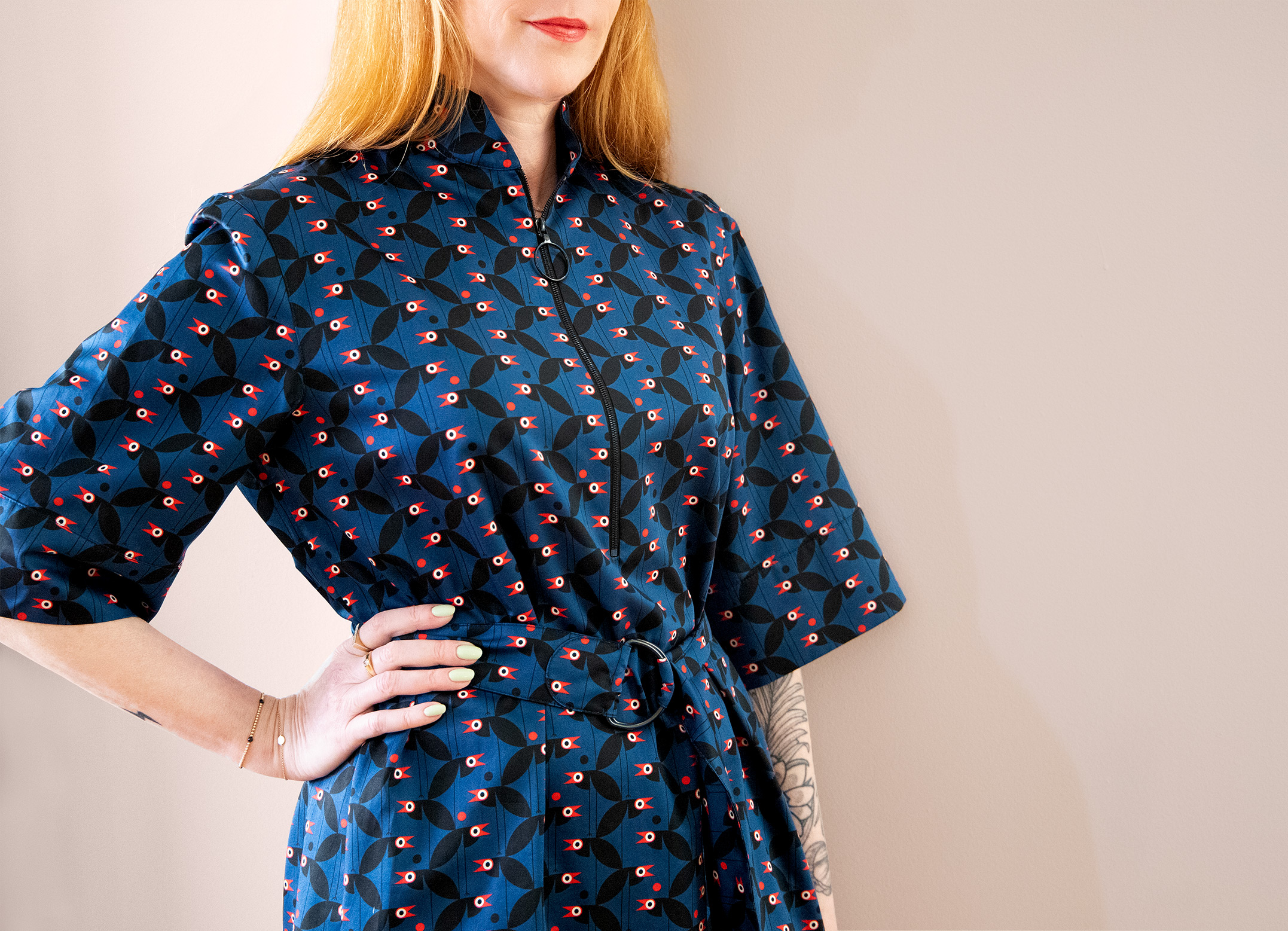 red haired woman with red lipstick and hand on hip wearing a cobalt blue shirt dress with crows pattern in black, white