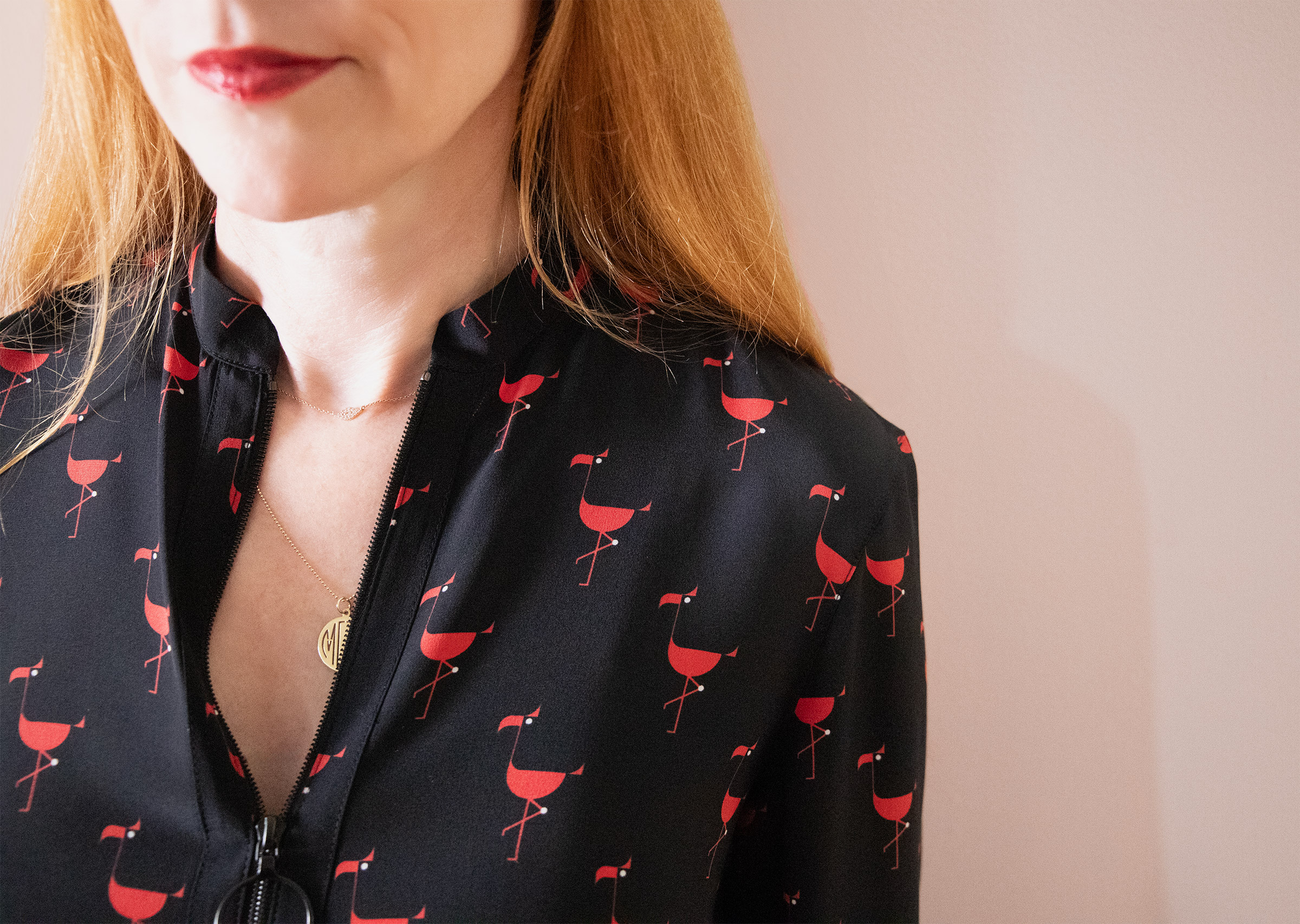 red haired woman close up wearing a black tunic with red flamingos