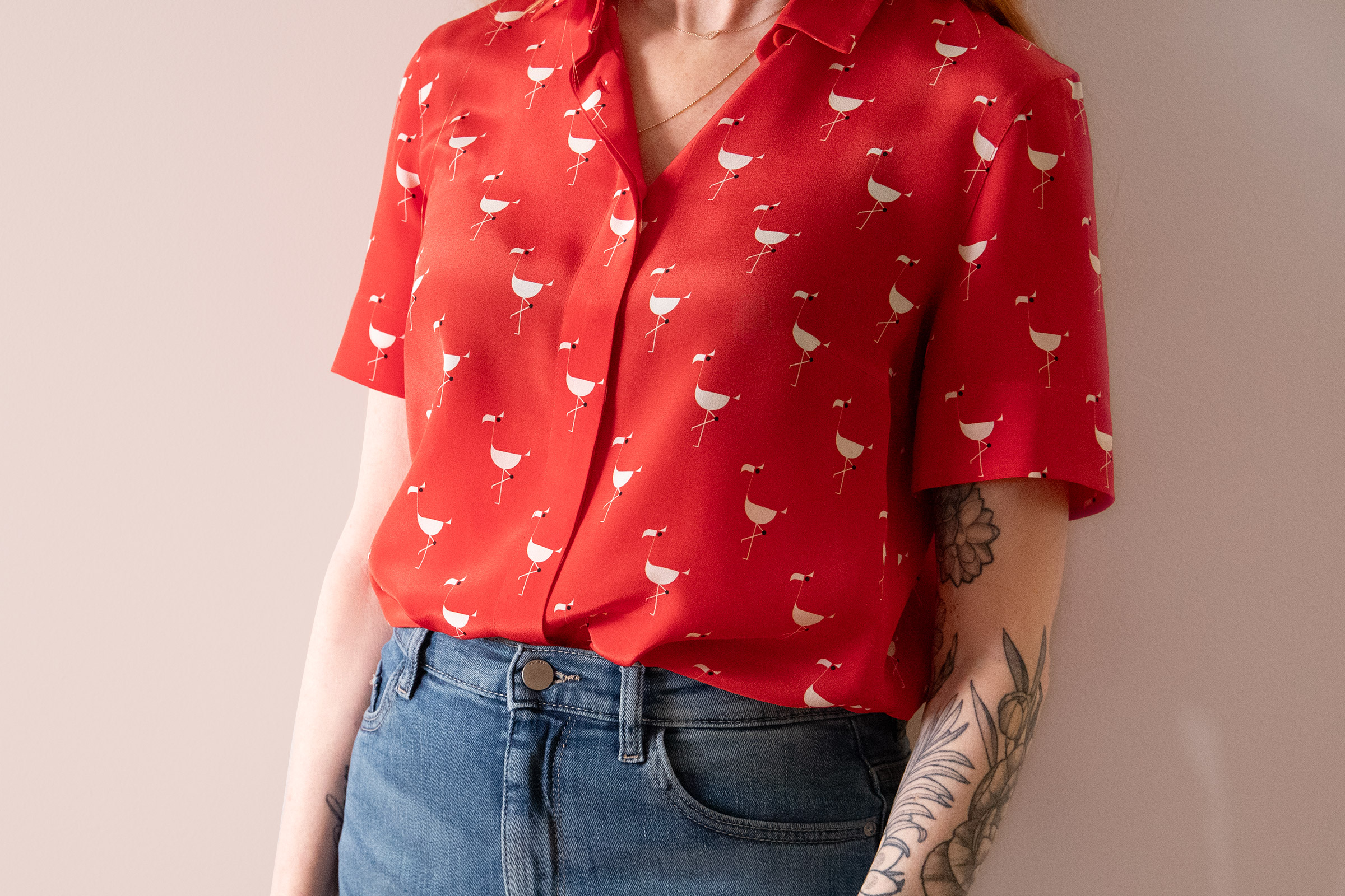 woman wearing a red silk shirt with white flamingos tucked into jeans